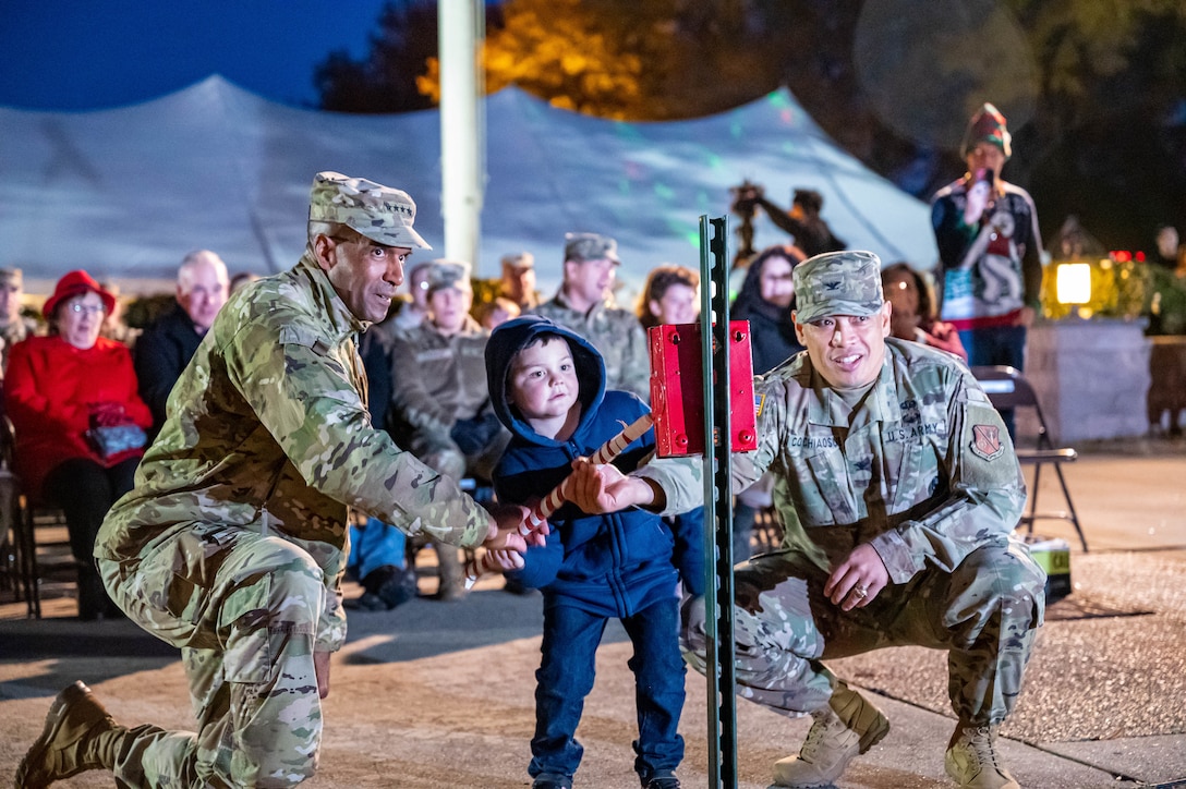 U.S. Army Gen. Gary Brito, Training and Doctrine Command commander (left), Jacob Connor and Col. Frankie Cochiaosue, 733d Mission Support Group commander flip the switch to turn on the holiday tree during the annual tree lighting ceremony at Joint Base Langley-Eustis, Virginia, Dec. 2, 2022.