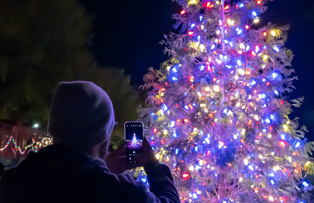 A member of the Fort Eustis community takes a photo of the holiday tree during the annual tree lighting ceremony at Joint Base Langley-Eustis, Virginia, Dec. 2, 2022.