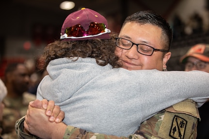 An Oklahoma Army National Guard Soldier hugs a family member at the deployment ceremony for Headquarters Battery, 45th Field Artillery Brigade in Mustang, Oklahoma, Dec. 3, 2022. The Soldiers are deploying to the US Central Command area of responsibility, providing headquarters operations to plan and execute supporting fires. (Oklahoma National Guard photos by Spc. Danielle Rayon)