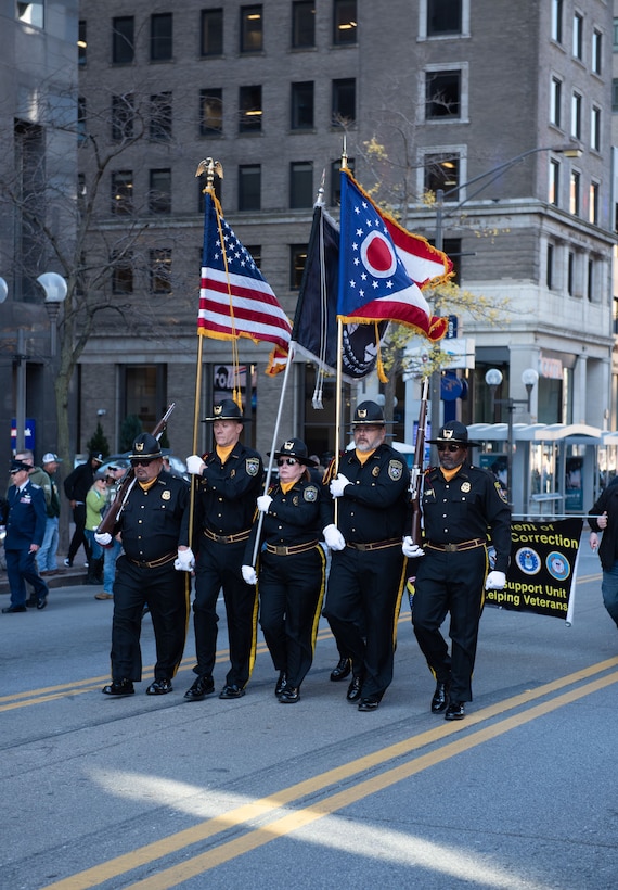 A four person police honor guard marches down the street.