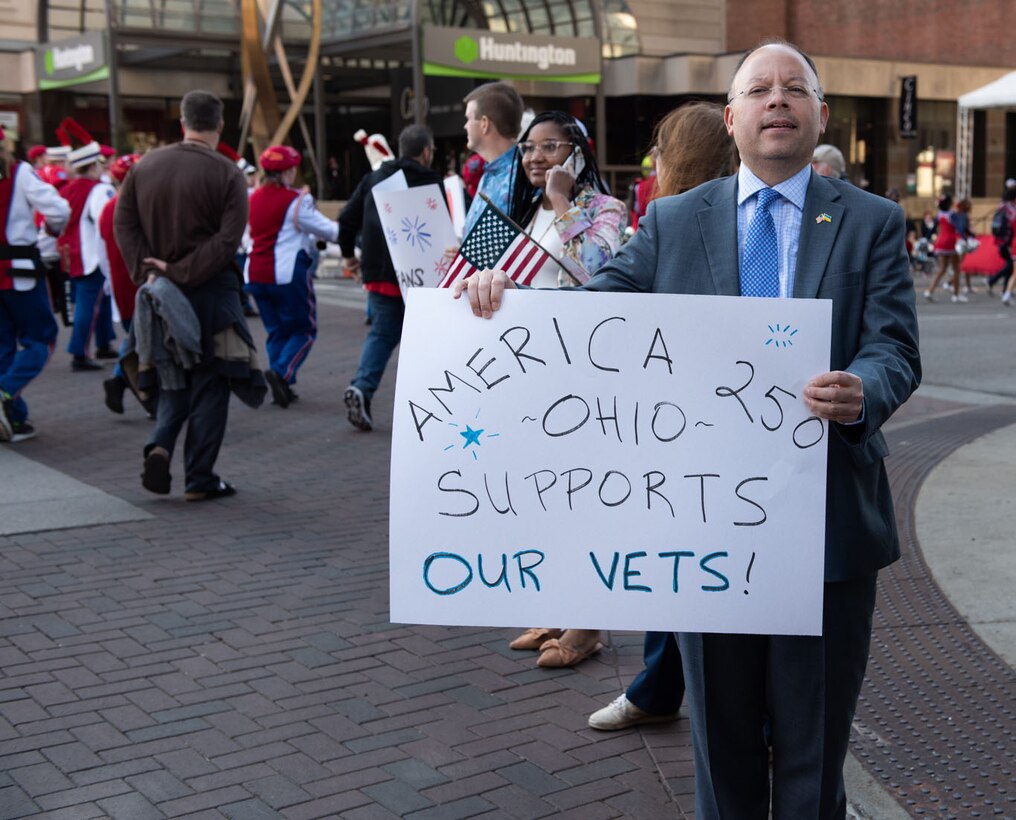 A man in a suit holds a sign while standing on the street.