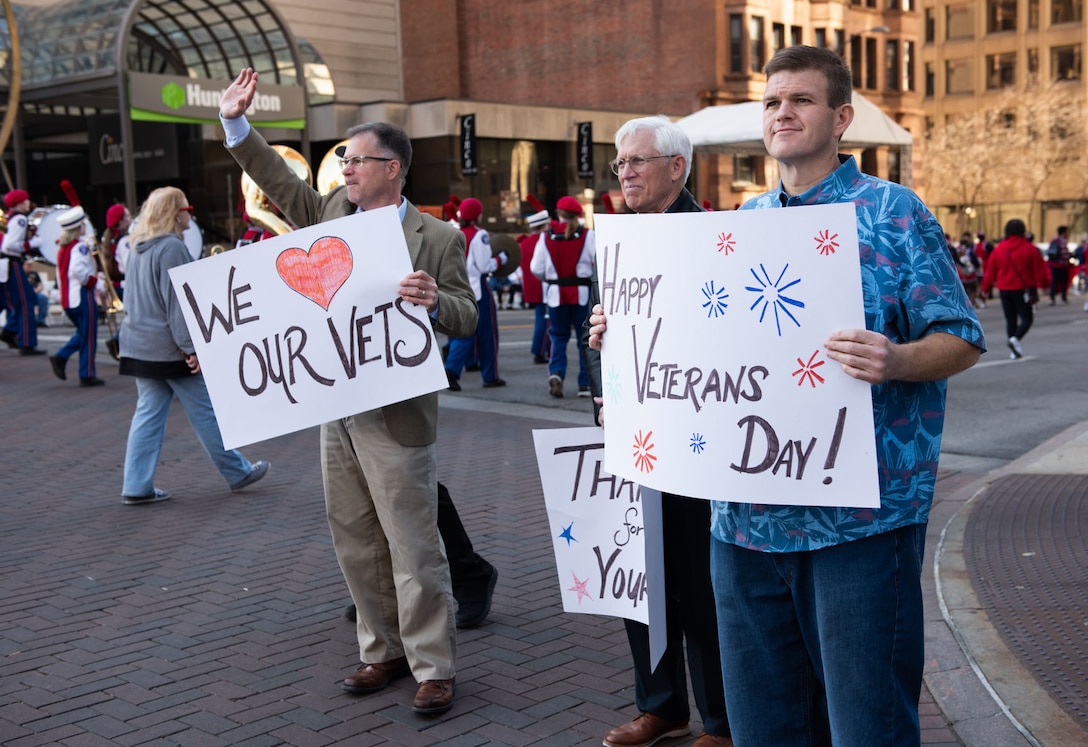 Several people hold signs while standing on the street.