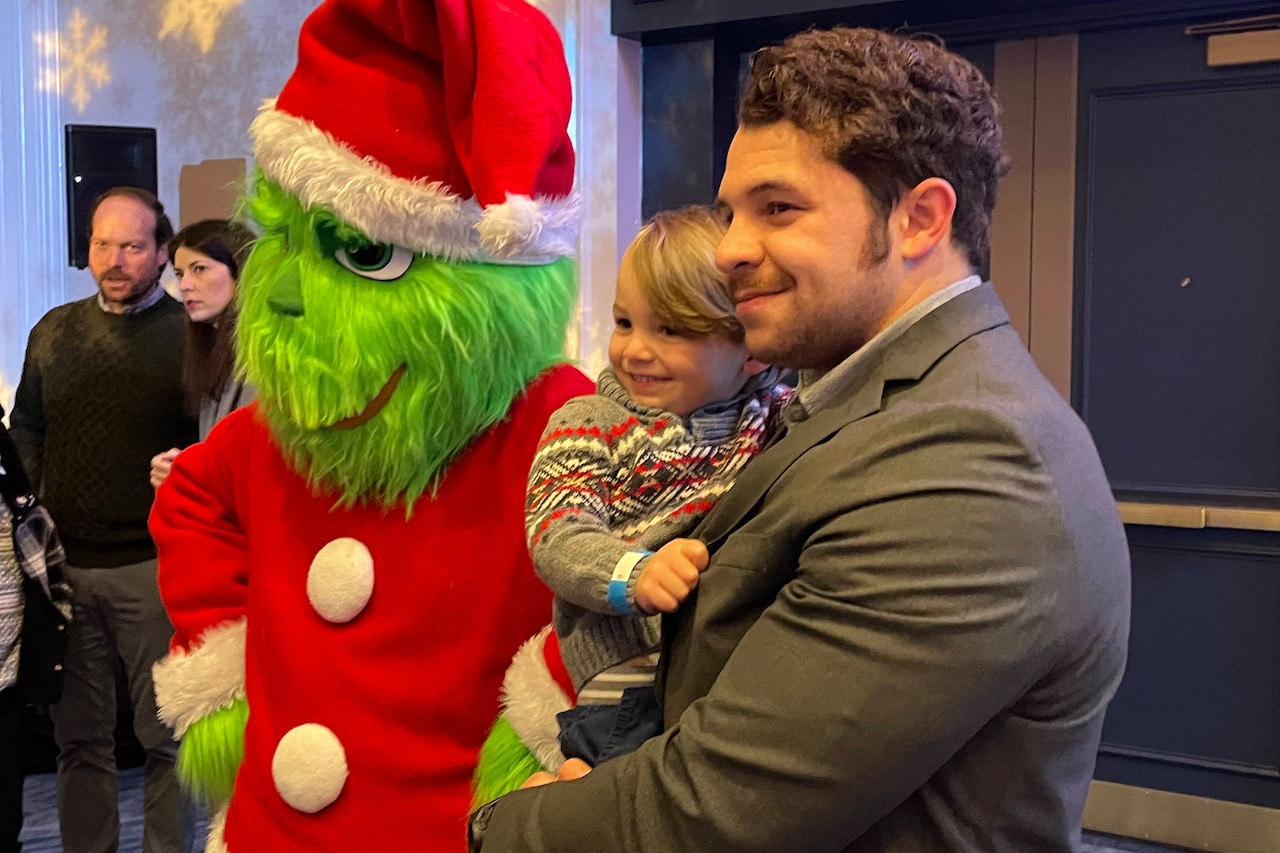 A man and a small child pose with a life-sized Grinch.