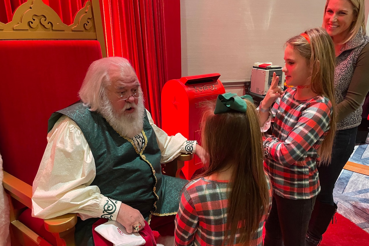 Two girls talk with Santa Claus.