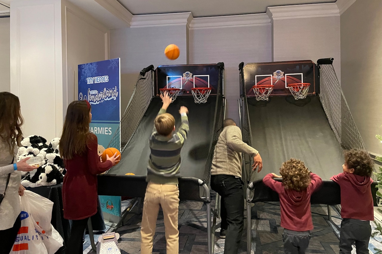 Four children play a basketball arcade game.