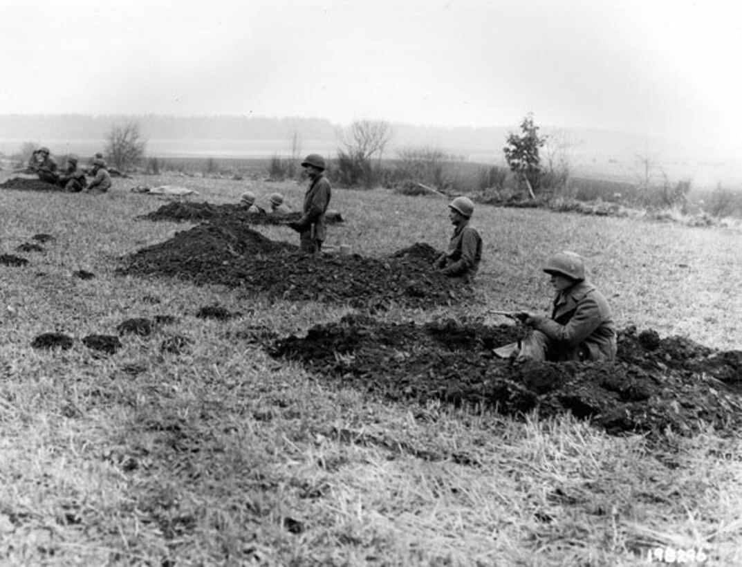 Soldiers of the 28th Infantry Division of the Pennsylvania National Guard, who had been regrouped into security platoons for defense of Bastogne, Belgium, man fighting positions, Dec. 20, 1944. Some of these Soldiers lost their weapons during the German advance in this area. (Signal Corps Photo #ETO-HQ-44-30380 by Tec 5 Wesley B. Carolan)