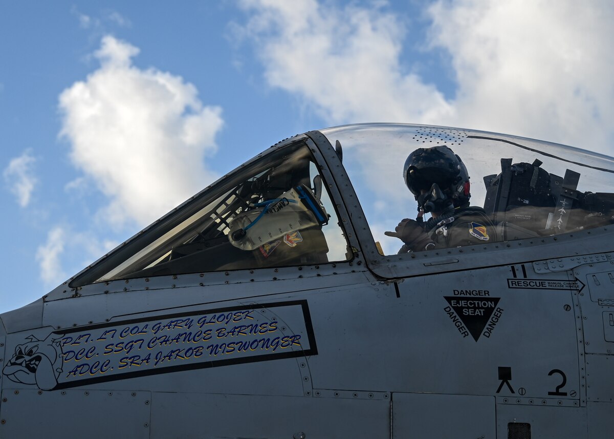 A photo of a pilot in a military uniform in the cockpit of a military aircraft.