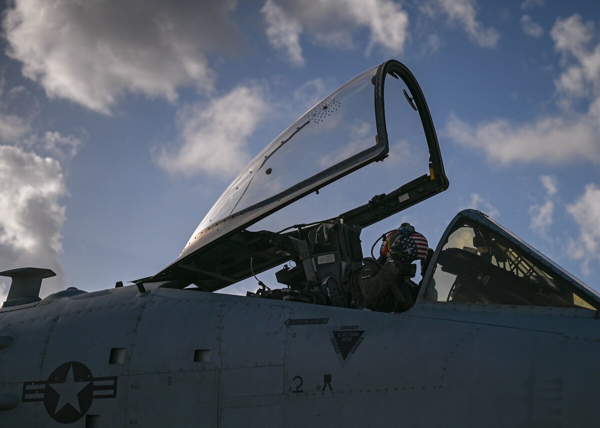 A photo of a pilot in a military uniform in the cockpit of a military aircraft.