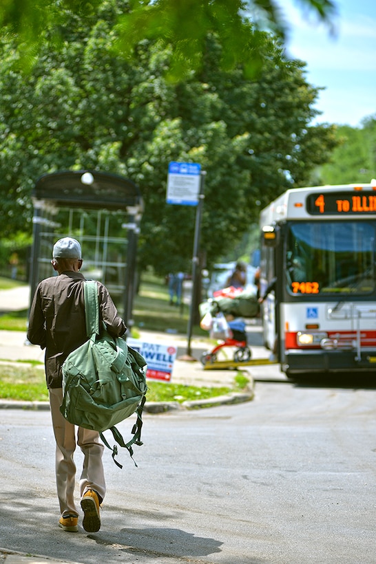 A man walks toward a bus stop.