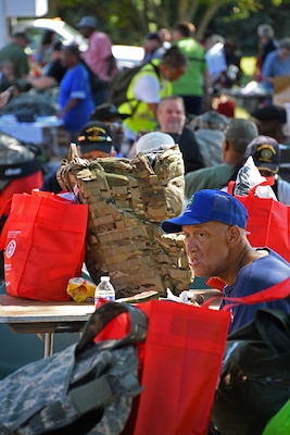 A man eats lunch surrounded by bags of surplus and other veterans.