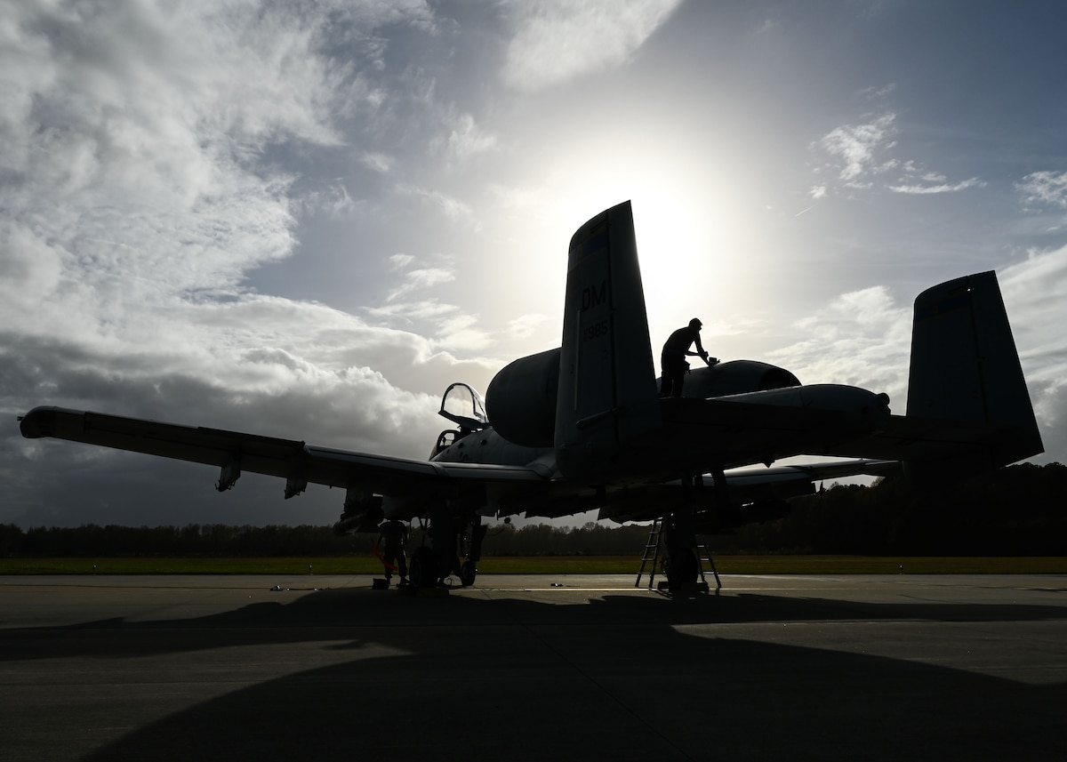 A photo of a person in a military uniform working on a military aircraft.