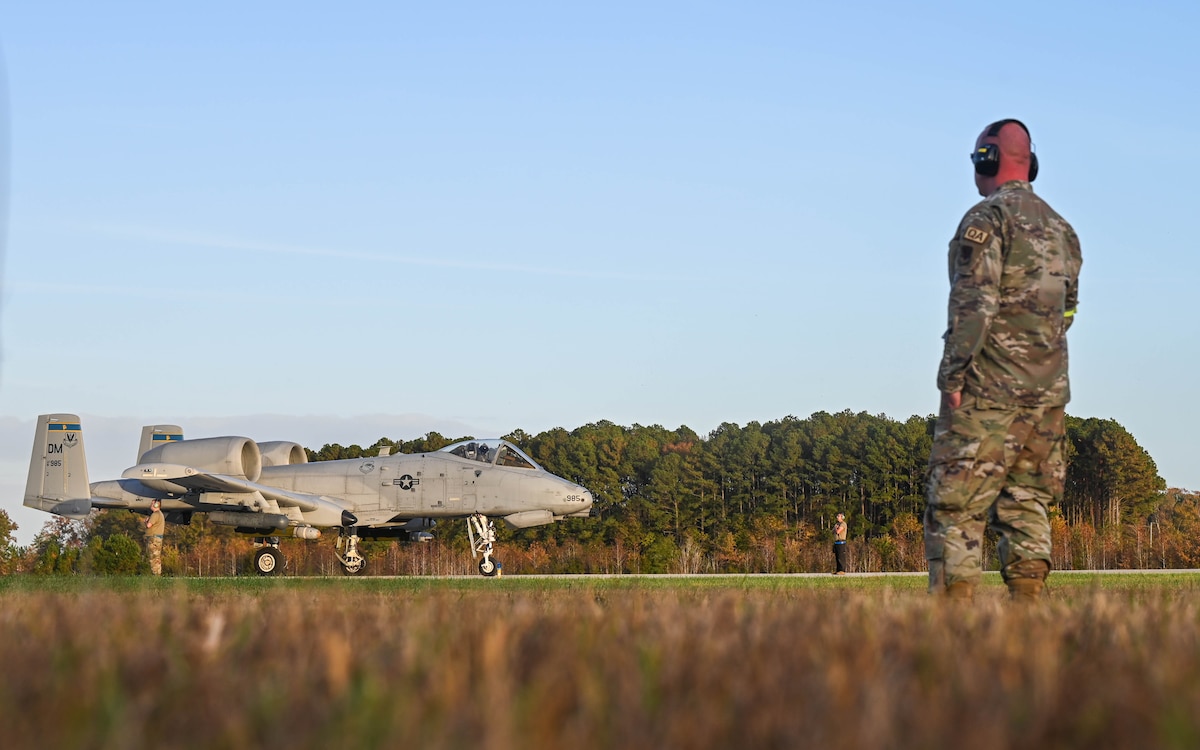 A photo of a man in a military uniform looking a military aircraft.