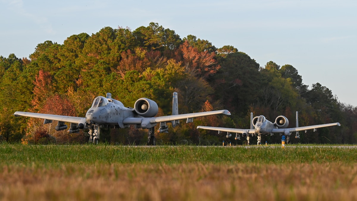 A photo of two military aircraft taxing on a runway.