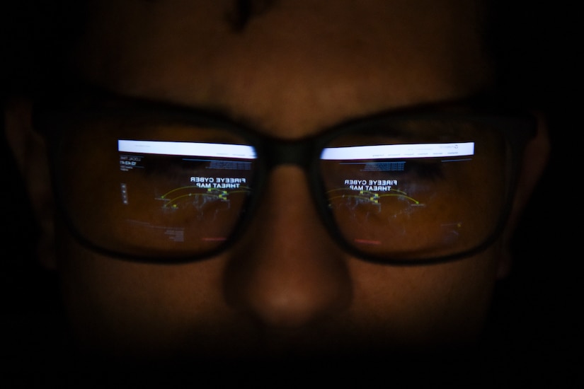 A man wears glasses that reflect a computer screen.