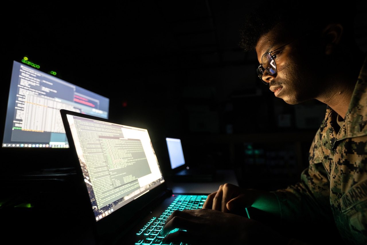 A service member uses a computer in a dark room.