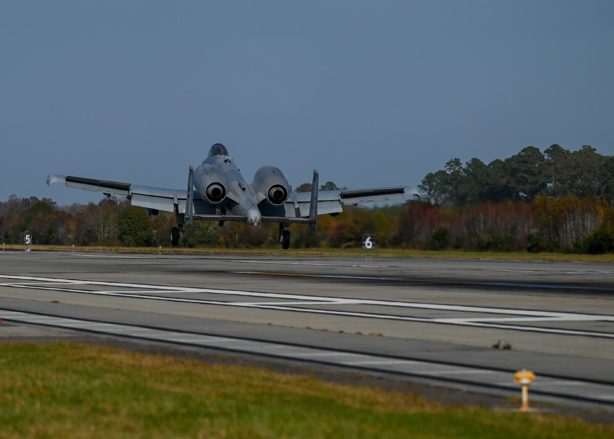 A photo of a military aircraft landing on a runway.