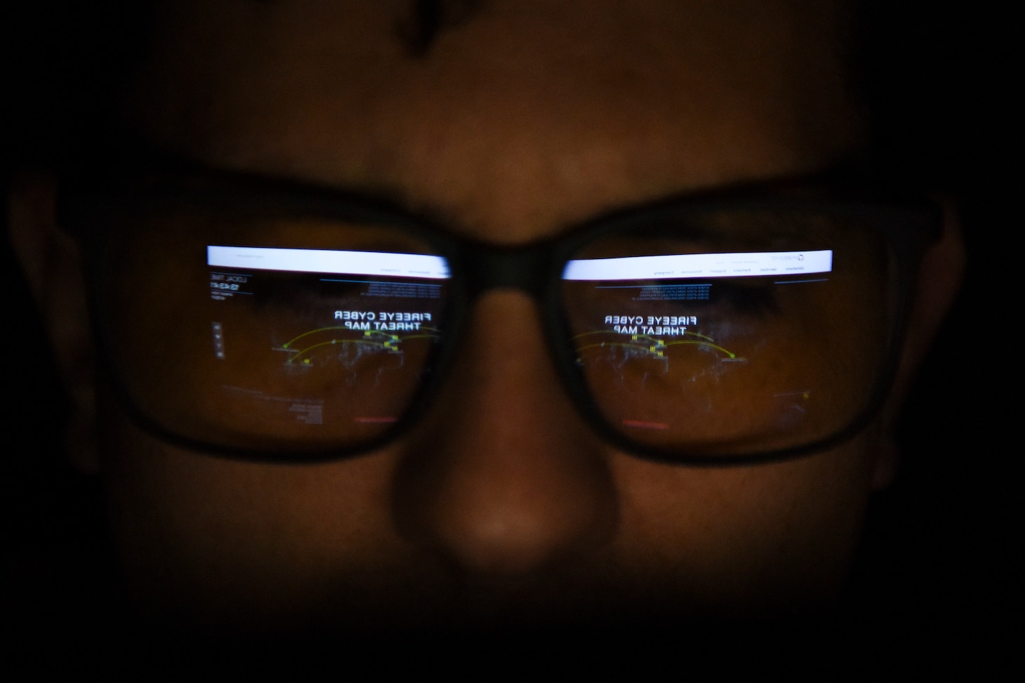 A man wears glasses that reflect a computer screen.