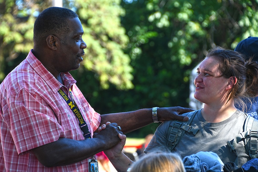 A man shakes hands with a woman as they talk.