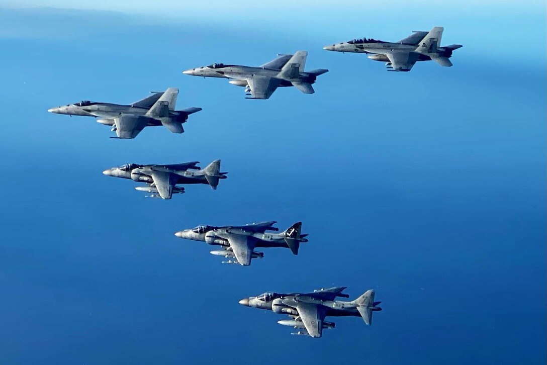 Six aircraft fly in formation over water.