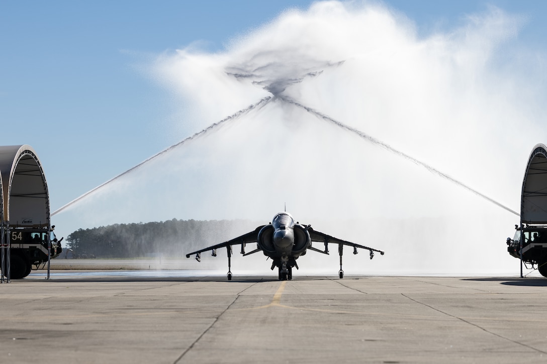 A military jet taxis under two streams of water.