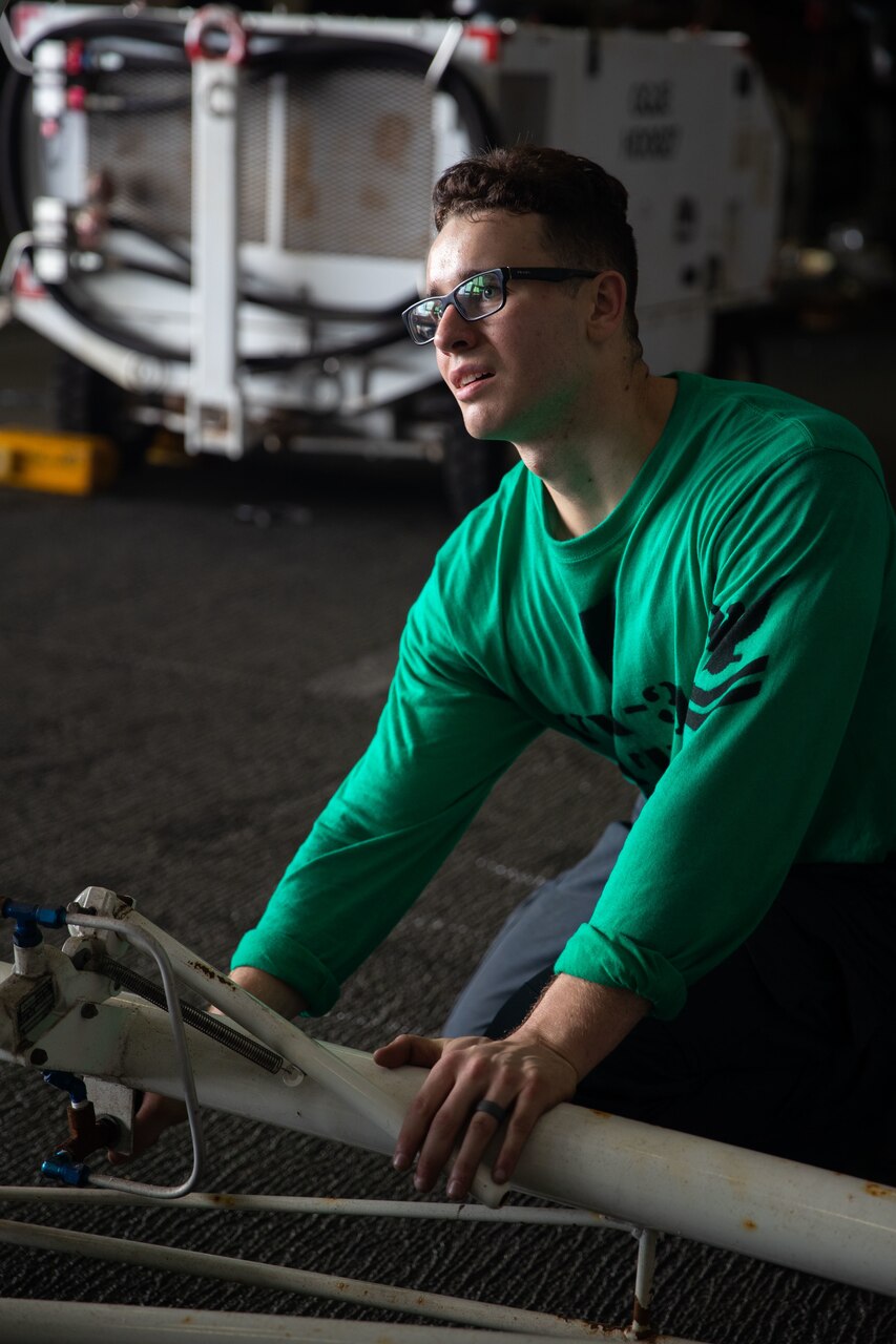 Aviation Electronics Technician 2nd Class Daniel Patrick Black, from St. Augustine, Florida, assigned to the “Tomcatters” of Strike Fighter Squadron (VFA) 31, raises a ladder during routine maintenance on an F/A-18E Super Hornet in the first-in-class aircraft carrier USS Gerald R. Ford's (CVN 78) hangar bay, Oct. 8, 2022.