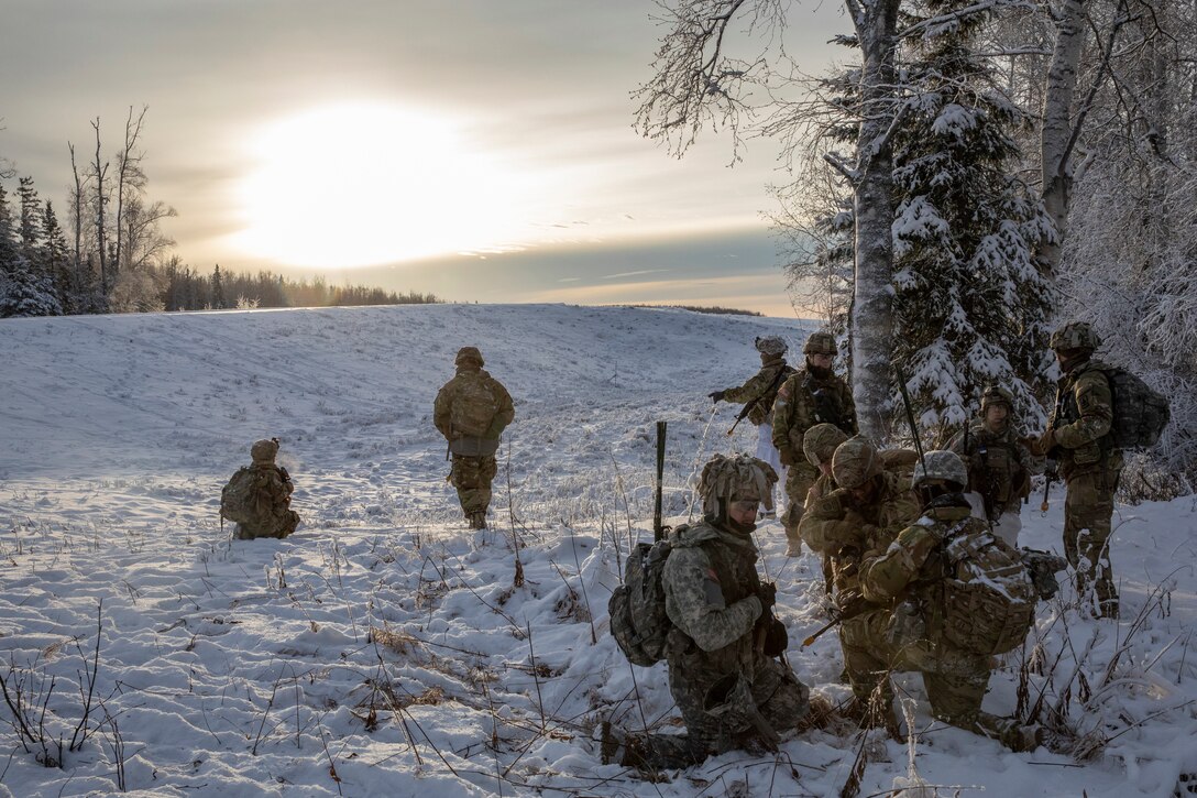 A group of soldiers train in the snow at twilight.