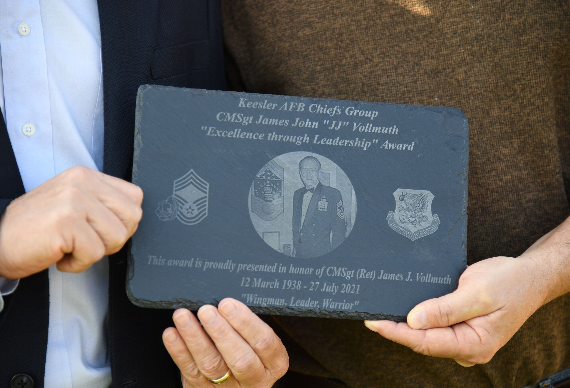 Retired U.S. Air Force Lt. Col. Mike Vollmuth and his brother, Jay Vollmuth, hold a plaque in honor of their father, retired Chief Master Sgt. James John "JJ" Vollmuth, prior to the 2nd Annual Chiefs vs. Eagles softball game at MGM Park in Biloxi, Mississippi, Dec. 5, 2022.