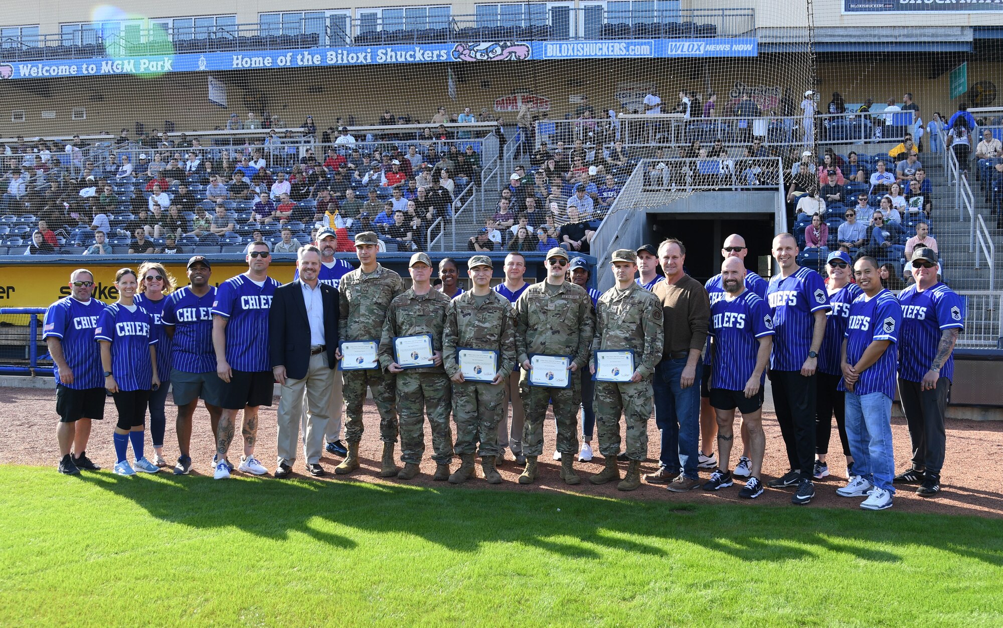 Keesler Air Force Base chief master sergeants pose for a photo with recipients of the Retired Chief Master Sgt. James John "JJ" Vollmuth Excellence Through Leadership Award prior to the 2nd Annual Chiefs vs. Eagles softball game at MGM Park in Biloxi, Mississippi, Dec. 5, 2022.