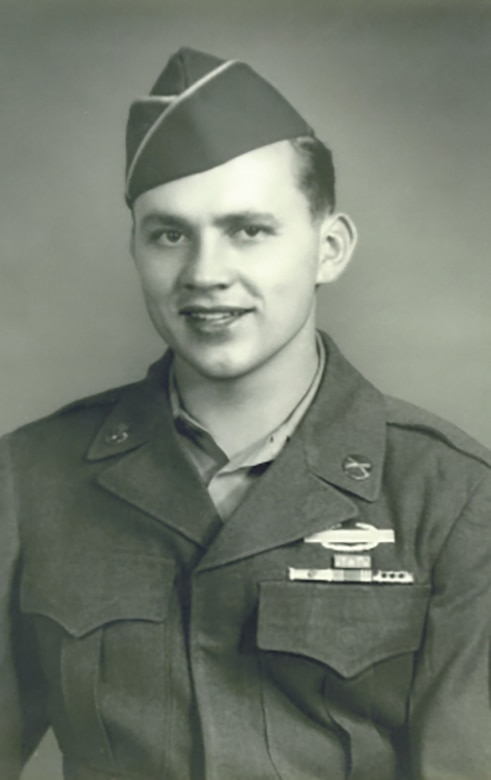 A man in uniform and cap poses for a photo.