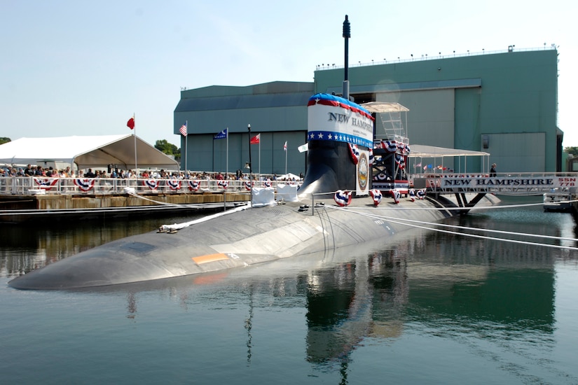 People crowd on a dock to look at a submarine.