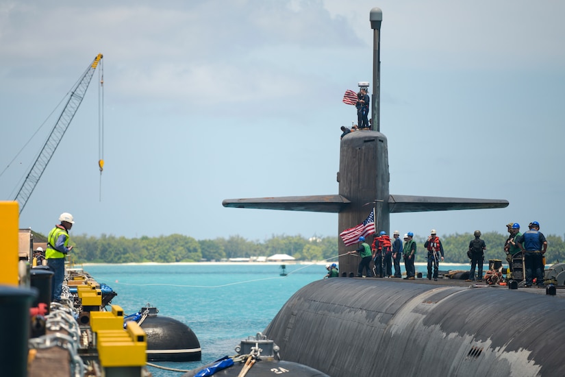 A submarine is docked at a pier.