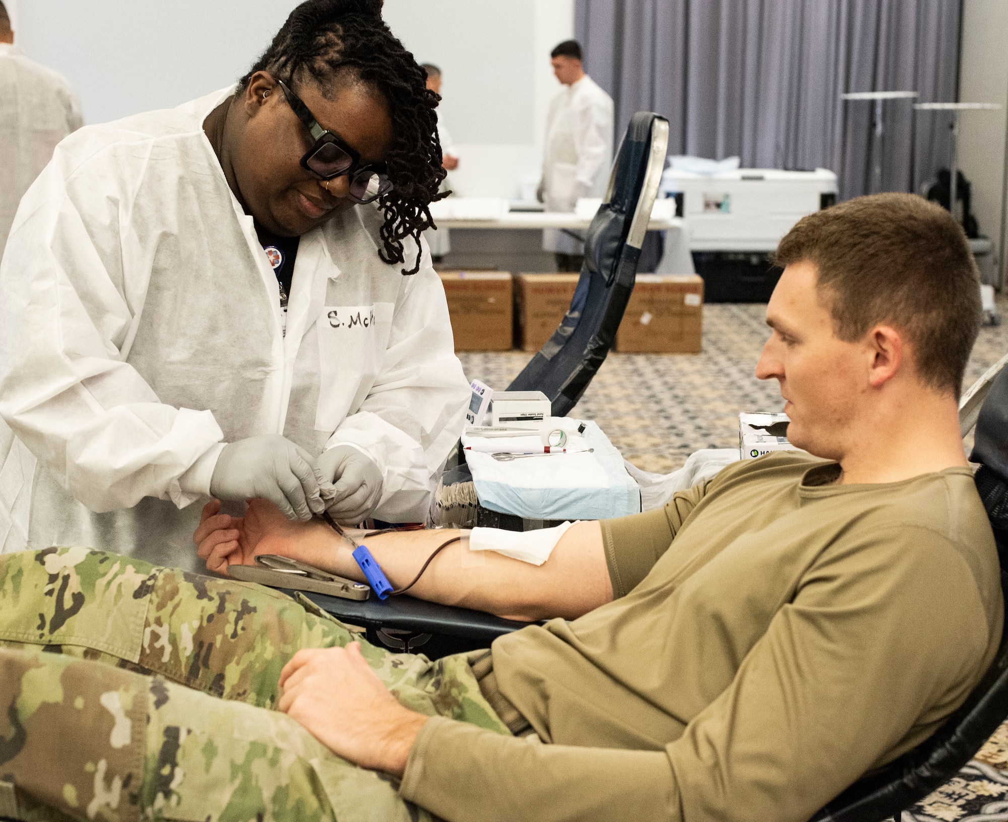 Shennia McKoy, left, Fort Bragg Blood Donor Center contract phlebotomist, prepares medical tubing on the arm of Staff Sgt. Craig Green, Armed Forces Medical Examiner System forensic laboratory technician, before donating blood on Dover Air Force Base, Delaware, Dec. 6, 2022. Green and other Team Dover members donated blood during the Armed Services Blood Program blood drive held at The Landings. (U.S. Air Force photo by Roland Balik)