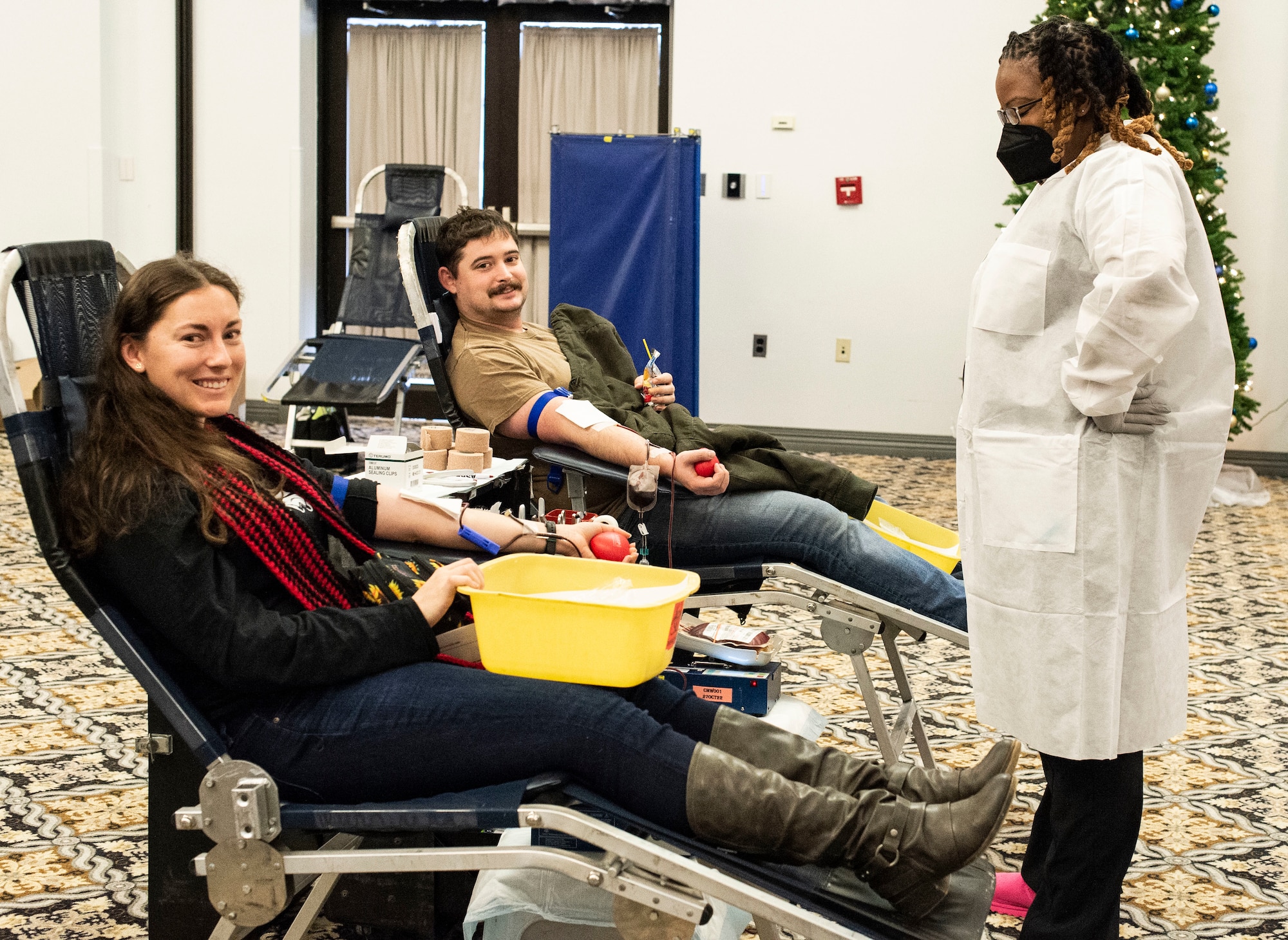 Airman 1st Class Amanda Jett, left, 436th Airlift Wing Public Affairs specialist, and her husband Edward, center, donate blood as Michele Imes, Fort Bragg Blood Donor Center contract phlebotomist, monitors them during the Armed Services Blood Program blood drive held at The Landings on Dover Air Force Base, Delaware, Dec. 6, 2022. The Jett’s and 51 Team Dover members donated during the blood drive. (U.S. Air Force photo by Roland Balik)