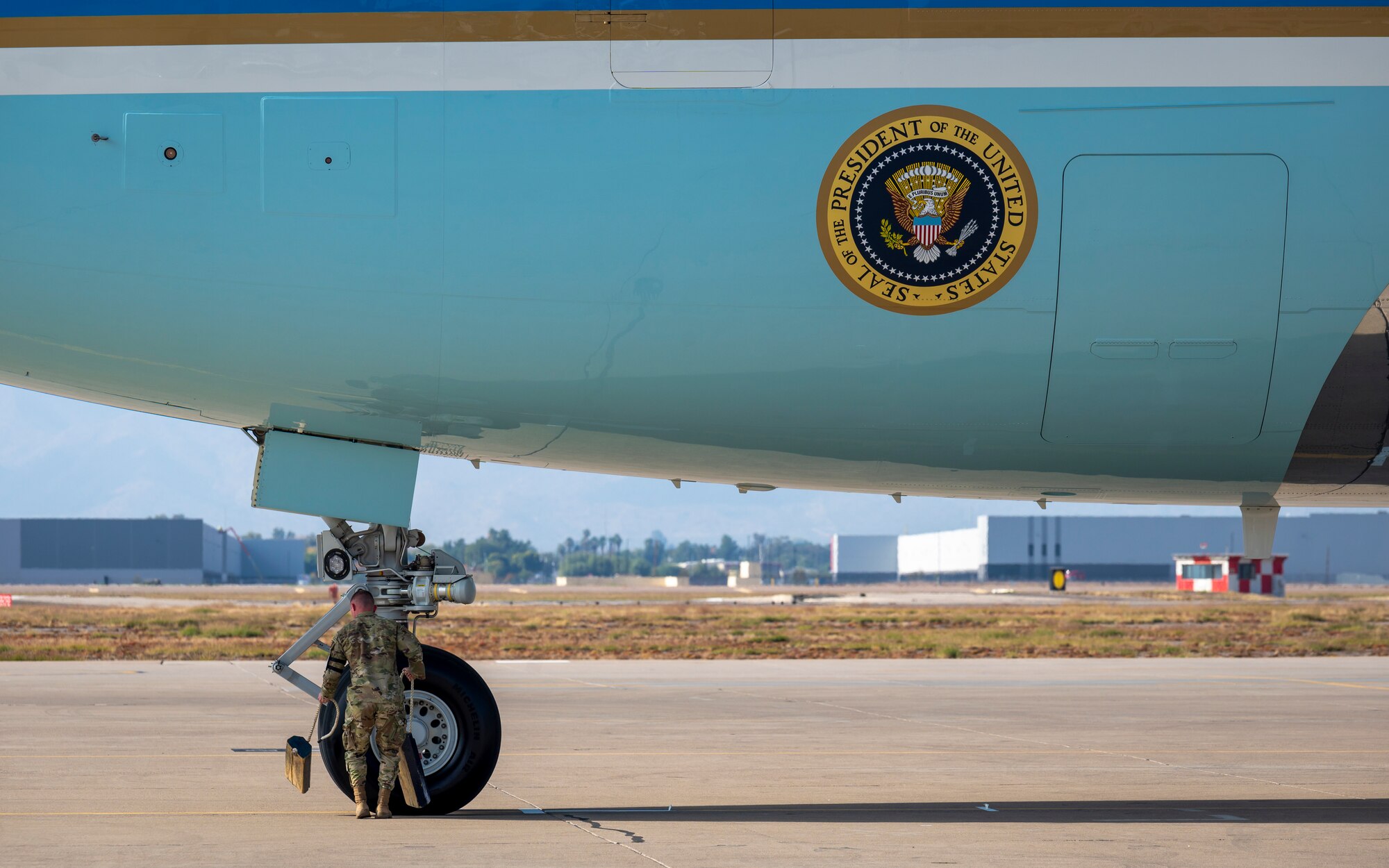 U.S. Air Force Senior Airman Irven Cheney, 56th Equipment Maintenance Squadron journeyman, places wheel chocks under Air Force One at Luke Air Force Base, Arizona, Dec. 6, 2022.