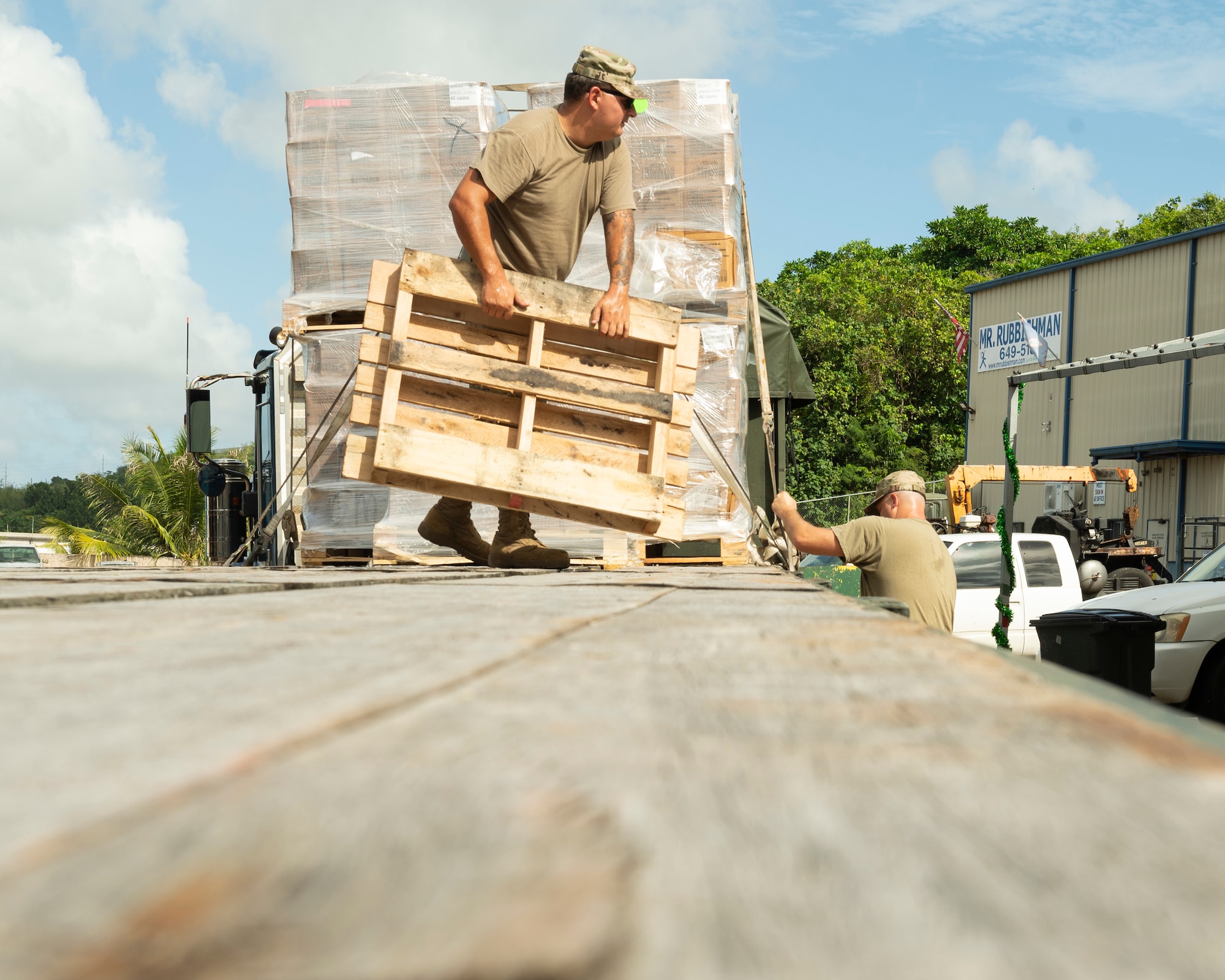U.S. Air Force Tech. Sgt. Charles Hall, noncommissioned officer in charge of training with ground transportation assigned to the 36th Logistics Readiness Squadron, moves a pallet while Tech. Sgt. Gregory Allen, a noncommissioned officer with the 36th LRS, tightens a strap to hold down pallets of ready-to-eat meals in Dededo, Guam, Nov. 30, 2022. Members of the ground transportation team moved about 50,000 pounds of cargo in support of the 71st Operation Christmas Drop. (U.S. Air Force photo by Airman Spencer Perkins)