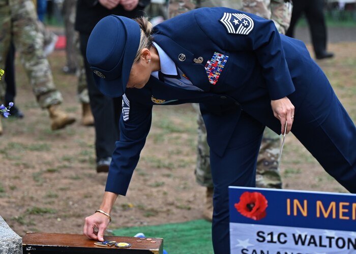 U.S. Air Force Chief Master Sgt. Rebecca Arbona, 17th Training Wing command chief, places her challenge coin on a piece of the USS Arizona after the Pearl Harbor Remembrance Day ceremony at Fairmount Cemetery, San Angelo, Texas, Dec. 7, 2022. Arbona and other attendees placed coins on the memorial to symbolize to other visitors that someone had paid their respects. (U.S. Air Force photo by Senior Airman Ethan Sherwood)