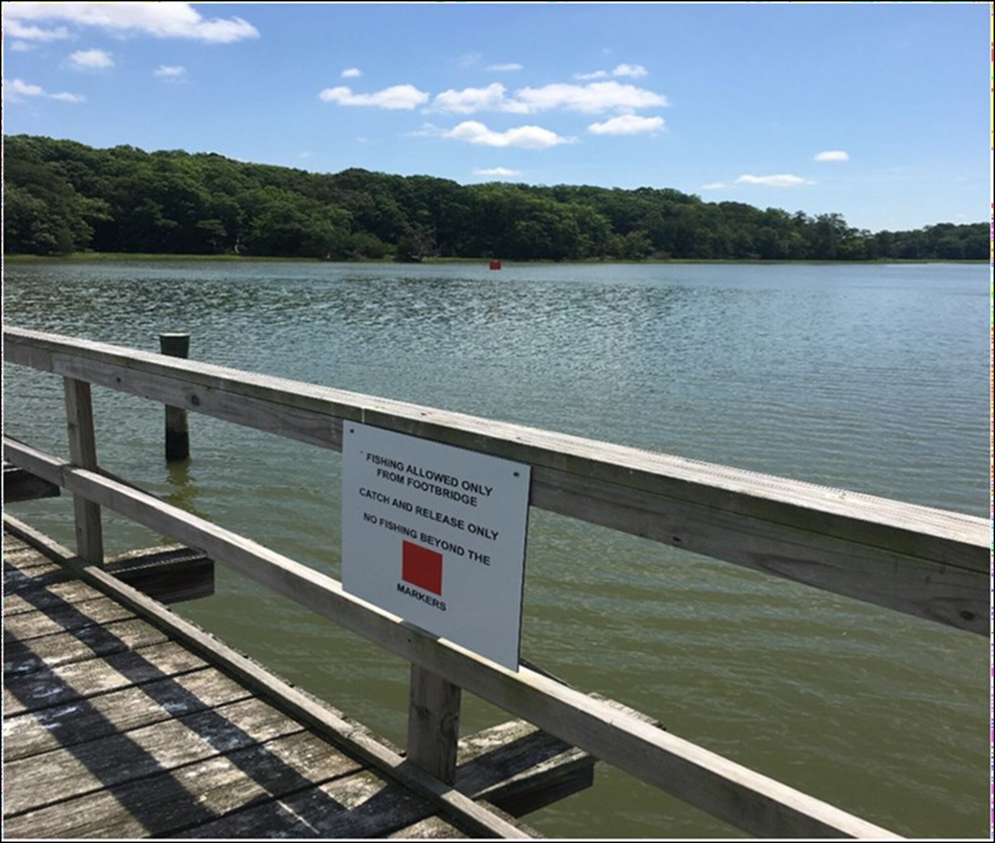 A sign denotes the rules of fishing from the Bailey Creek Footbridge at Joint Base Langley-Eustis, Virginia. Only catch and release fishing is allowed from the area.