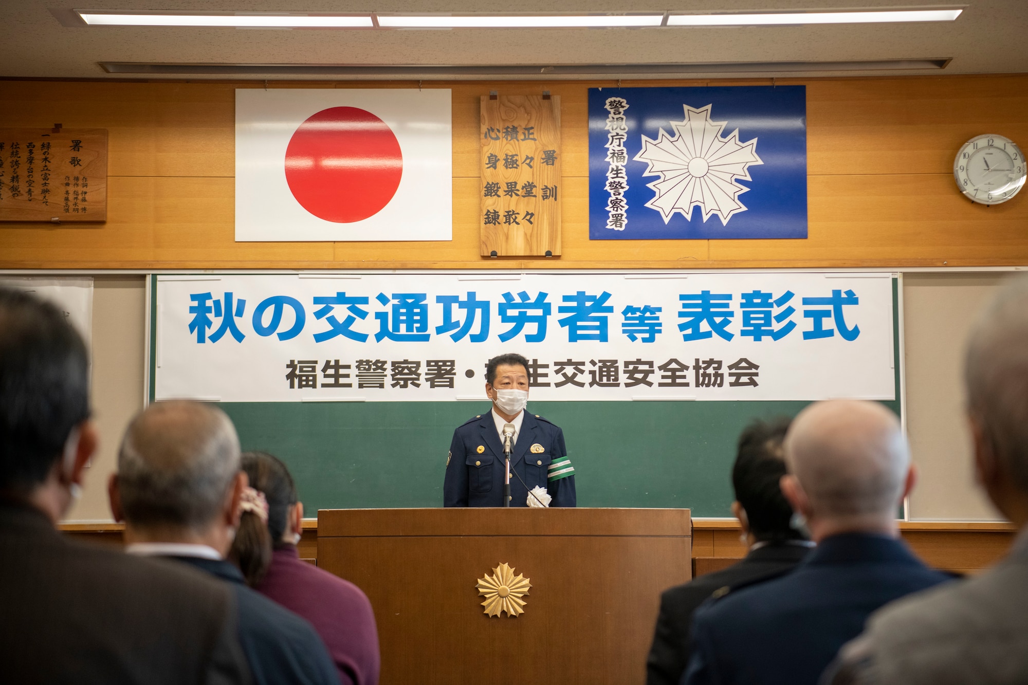 A man stands at a podium talking to recipients of safety awards presentation.