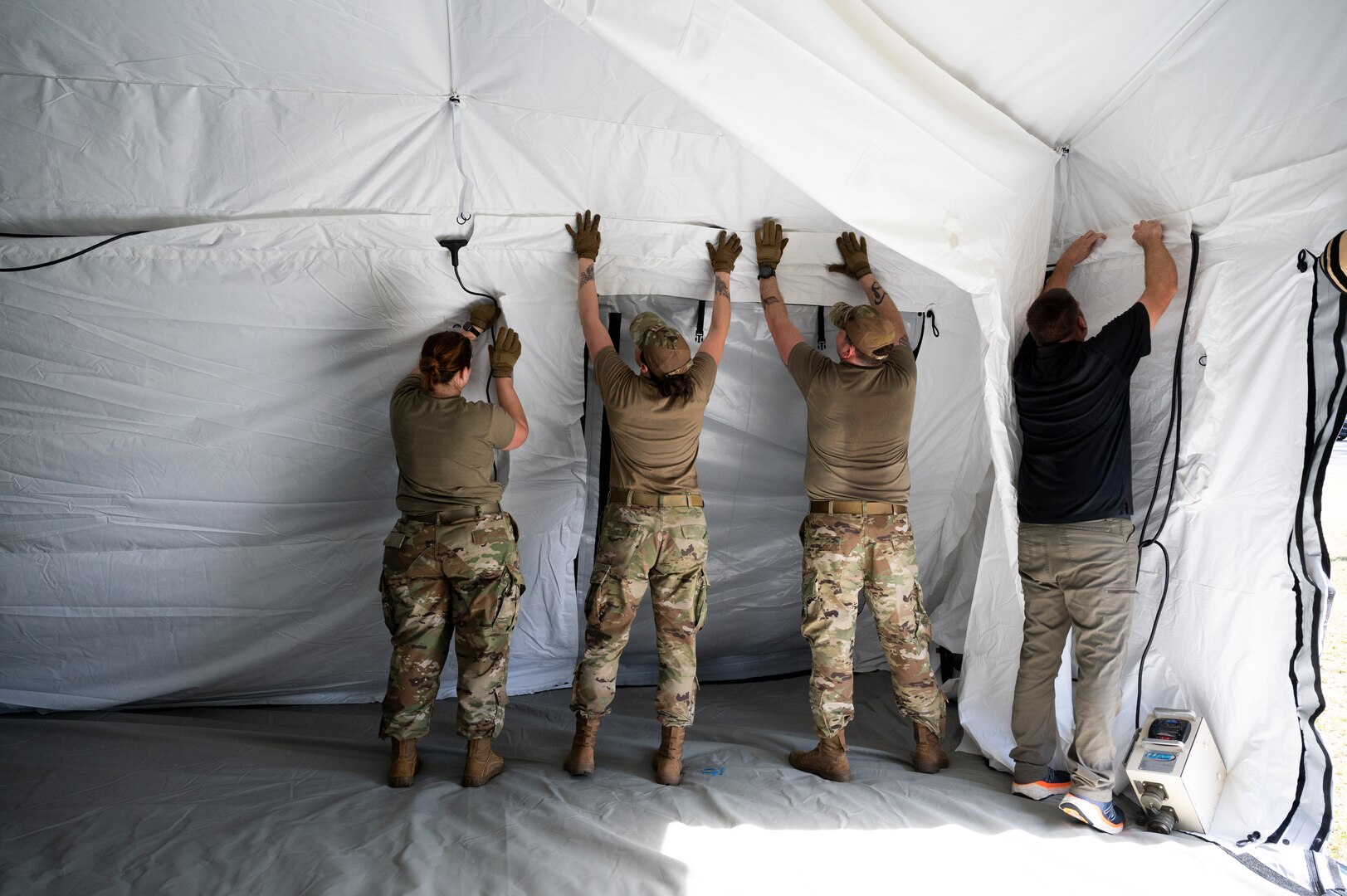 Photo of Airmen from the Alaska Air National Guard and contractors setting up a Tactical Shelter.