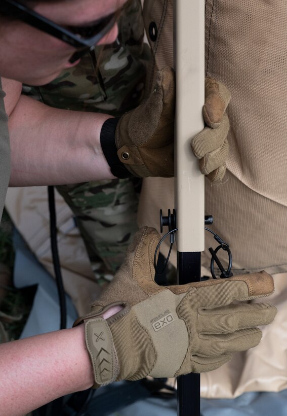 Photo of Airmen from the Alaska Air National Guard and contractors setting up a Tactical Shelter.