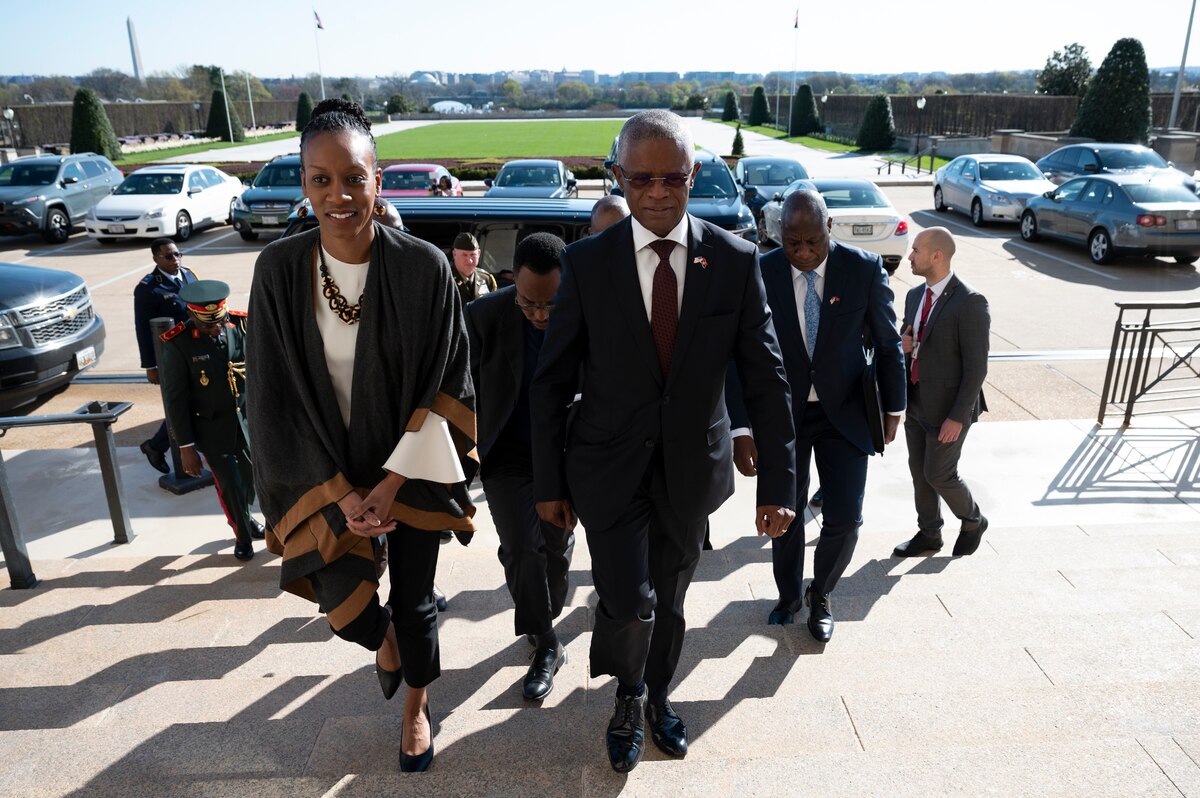 A man and woman walk up some stairs outdoors as others follow.