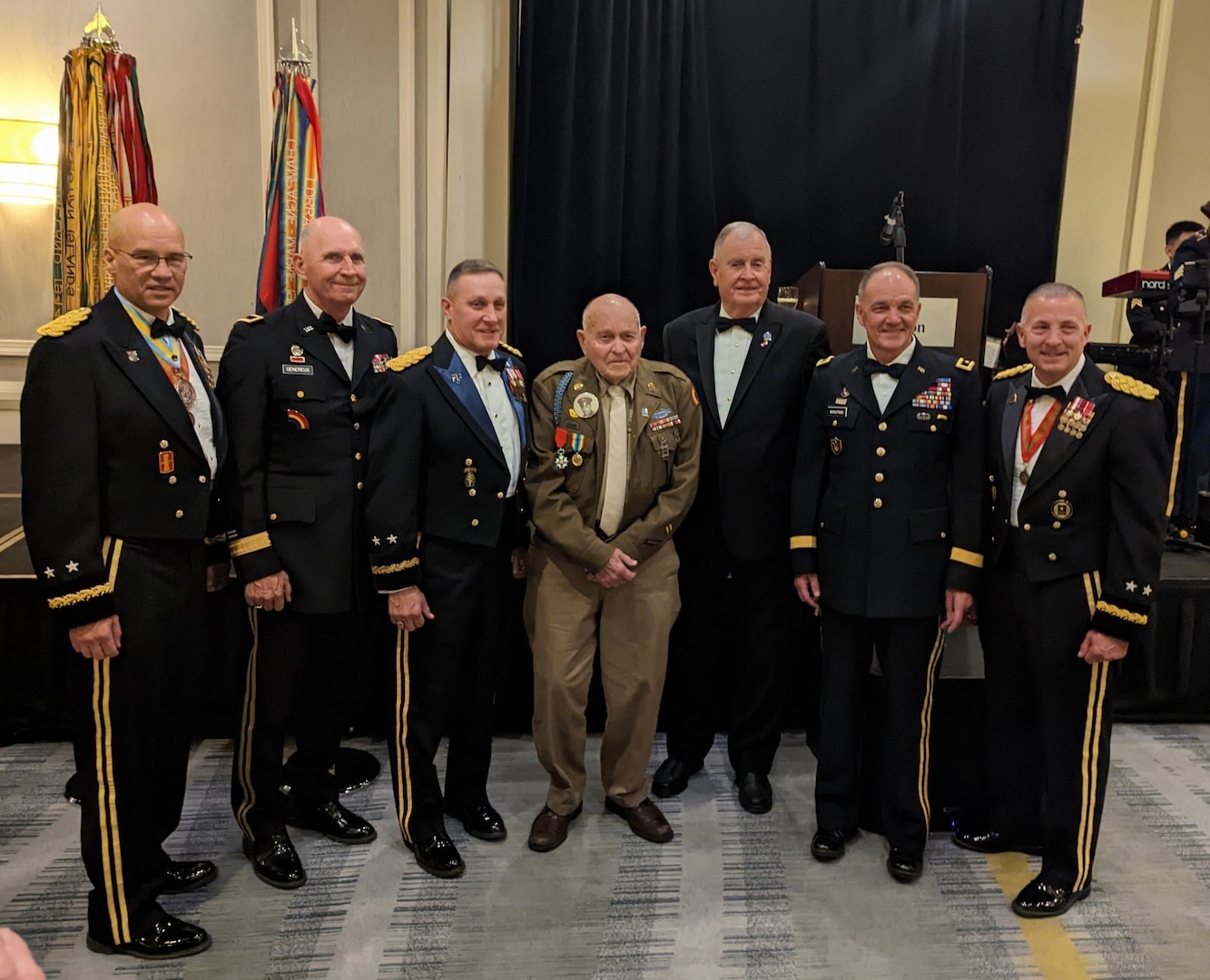 Lockered "Bud" Gahs from Perry Hall, Maryland, who served as a private in the 42nd Infantry Division's 222nd Infantry Regiment, shared his memories of World War II with 300 New York Army National Guard Soldiers Dec. 2, 2022, in Albany, New York. Left to right, Maj. Gen. Thomas Spencer, commanding general, 42nd Infantry Division, and former CGs: Brig. Gen. Paul Genereux, Maj. Gen. Harry Miller, Maj. Thomas Kinley, Maj. Gen. Steve Wickstrom, and Maj. Gen. Steve Ferrari. Gahs is in the middle.