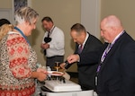 Three men serving breakfast to woman in buffet line.