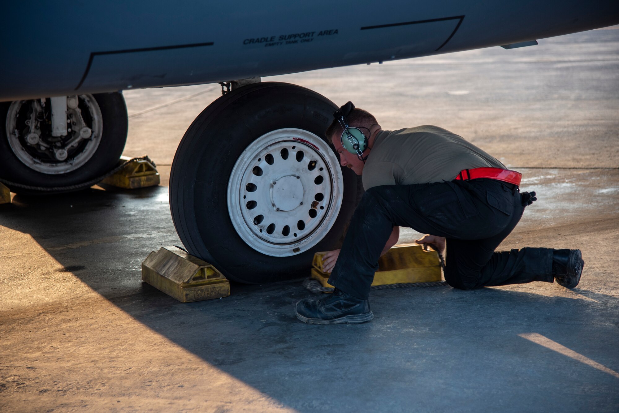 Airman 1st Class William Phillips, 389th Expeditionary Fighter Squadron crew chief, removes chocks from underneath an F-15E Strike Eagle at an undisclosed location, Southwest Asia, Nov. 15, 2022. These chocks prevent the jets from rolling when they aren't being operated. (U.S. Air Force photo by: Tech. Sgt. Jim Bentley)