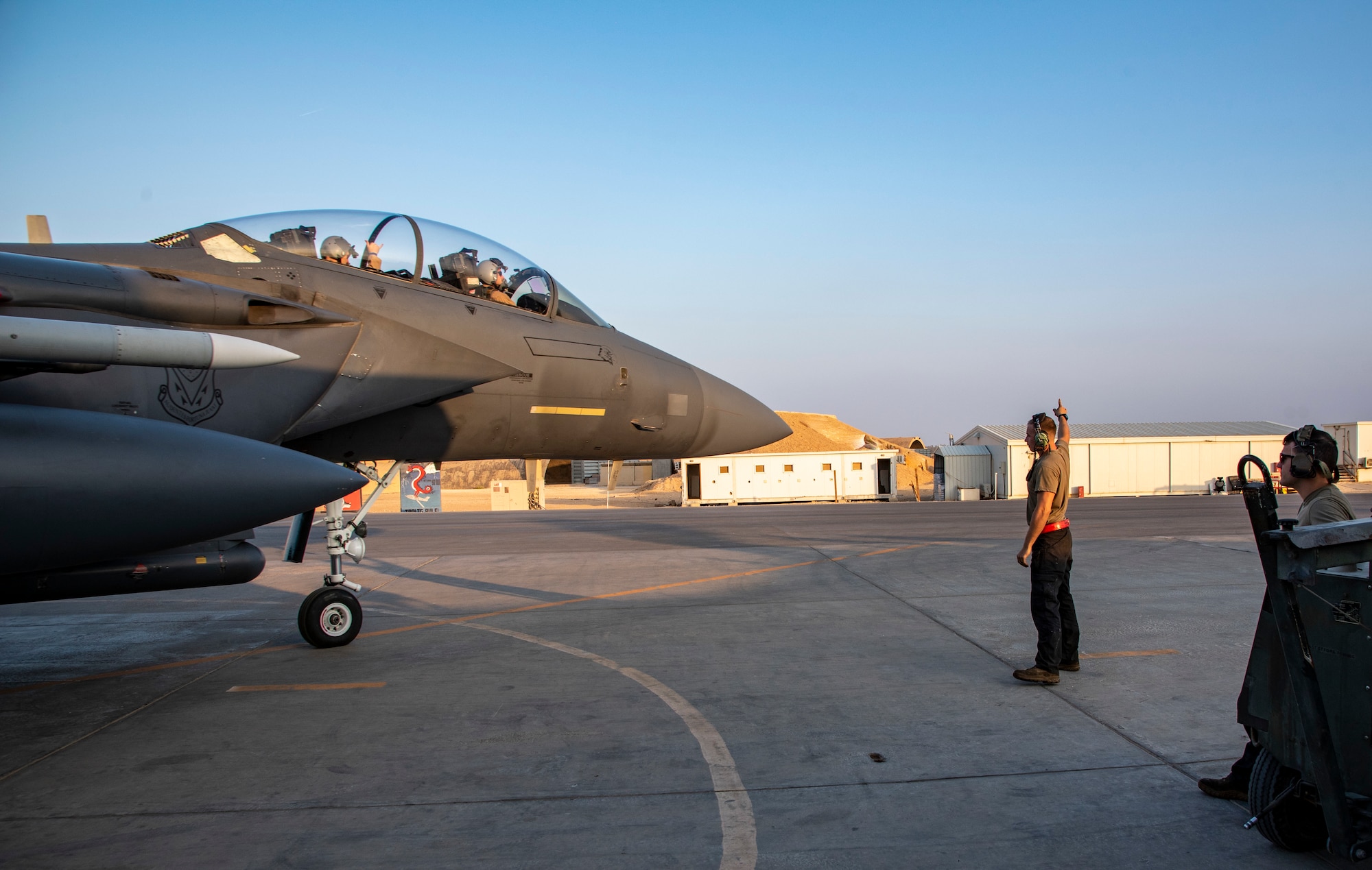 Airman 1st Class Leyton Wheeler, 332d Expeditionary Fighter Generation Squadron crew chief, taxis an F-15E Strike Eagle at an undisclosed location, Southwest Asia, Nov. 15, 2022. Capt. Benjamin Jones, pilot, and 1st Lt. Jacob Ferrer, systems operator, 389th Fighter Squadron, are on board ready to fly. He and Airman 1st Class William Phillips (right) were there to conduct a preflight inspection, ensuring that all systems are working properly, reducing the risk of in-flight emergencies. (U.S. Air Force photo by: Tech. Sgt. Jim Bentley)