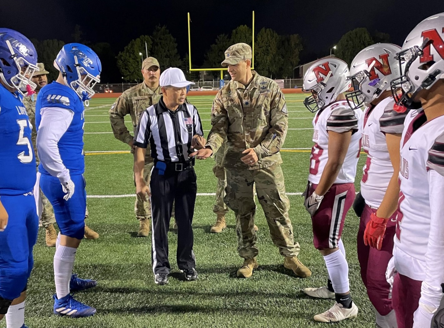 Image of Military officers on the football field with football players