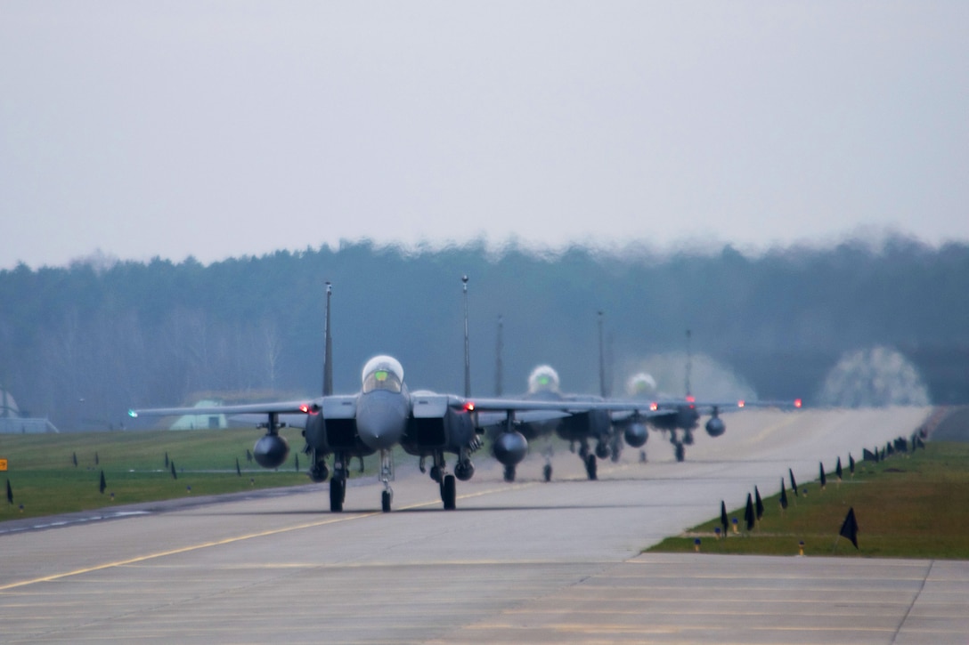 Six aircraft taxi on a runway.