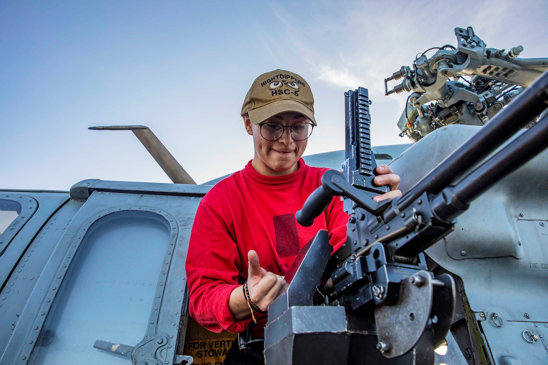 A sailor works on a machine gun.