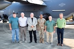 A group shot of five men in business attire and a female military leader in a military uniform