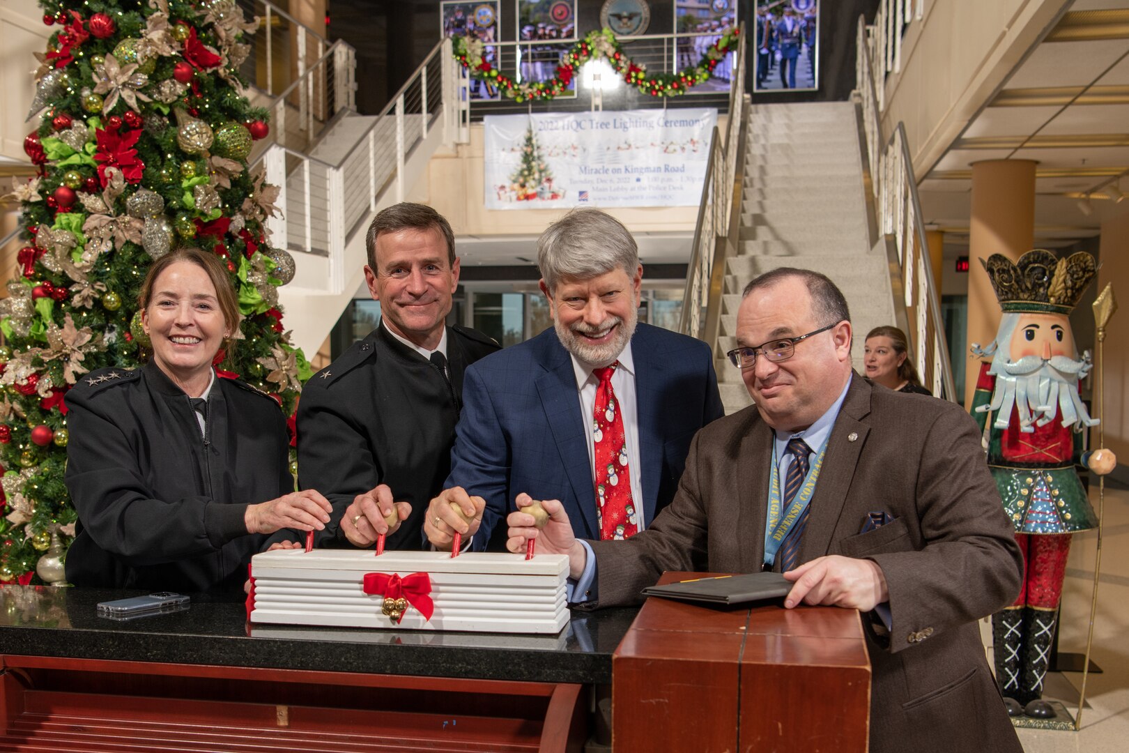 A group of people hit a switch to light a Christmas tree
